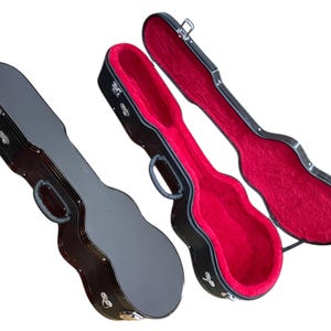Può includere: Tre custodie nere per chitarra. Una è chiusa, una è aperta e la terza è aperta. Gli interni delle custodie aperte sono foderati in velluto rosso. Ogni custodia ha una maniglia e ferramenta in metallo.