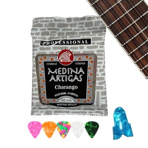 Könnte beinhalten: Eine Packung Medina Artigas Charango Nylonsaiten und eine Auswahl an farbigen Gitarrenplektren. Auf der Packung steht "Professional" und "Strings". Ein Teil eines Gitarrengriffbretts ist im Hintergrund zu sehen.