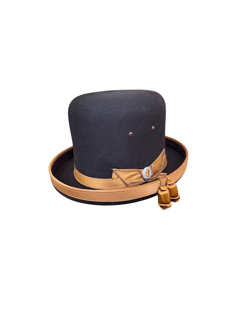 May include: A black felt fedora hat with a brown leather band and a gold ribbon. The hat has a small gold button on the front and two gold tassels.