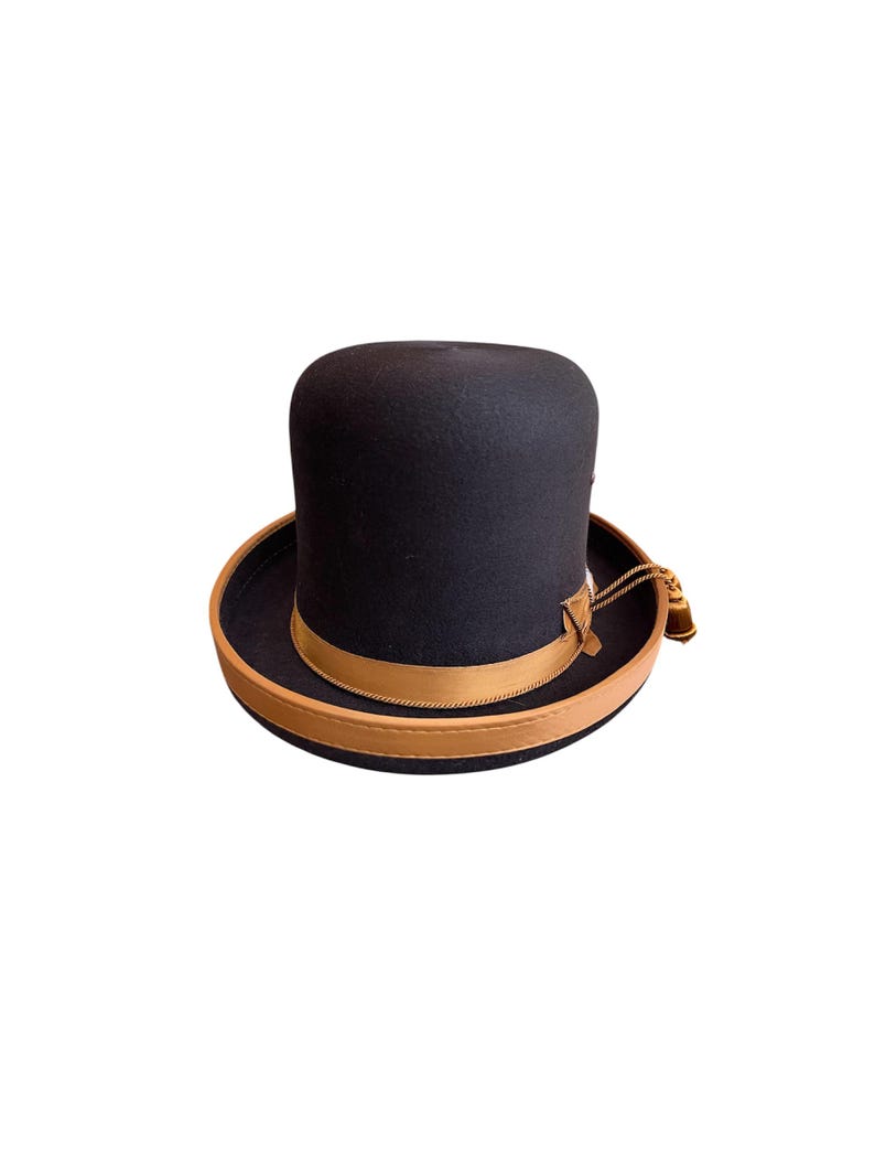 May include: A black felt top hat with a brown leather band and a gold tassel.