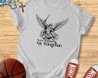 May include: A light gray t-shirt featuring a black and white illustration of an angel with a sword and wings. The text "Never Without My Wingman" is below the illustration. Red sneakers and a basketball are in the image.