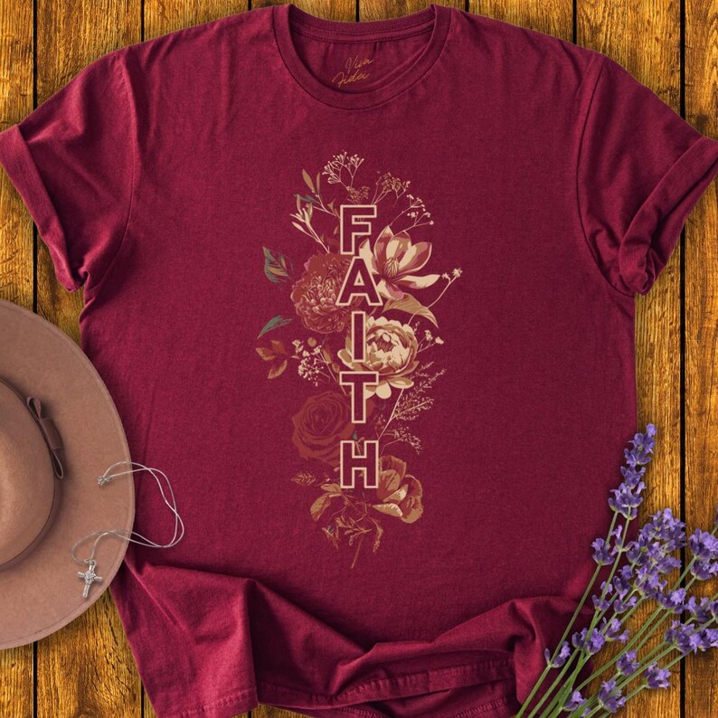 May include: Burgundy t-shirt with a floral design and the word "FAITH" in a vertical line.