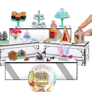 May include: A collection of miniature Harry Potter-themed food and decorative items, including cakes, candies, and potion bottles, arranged on tiered display tables. The items are brightly colored and detailed, with a hand reaching towards a miniature birdcage. A Mini Verse ball is in the foreground.