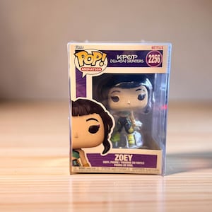 Könnte beinhalten: Eine Funko Pop! Vinyl-Figur von Zoey aus K-Pop Demon Hunters in einer transparenten Kunststoffvitrine. Die Box trägt das Funko Pop! Animation-Logo und das Netflix-Logo. Die Figur hat die Nummer 2256.
