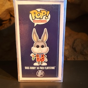 Puede incluir: Figura de vinilo Funko Pop! de Bugs Bunny disfrazado de Pedro Picapiedra, sosteniendo una zanahoria. La figura está en una funda protectora. El logo de Pop! Animation está en la parte superior, con el texto "BUGS BUNNY 'AS FRED FLINTSTONE'" y el número 1259.