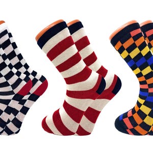 May include: Three pairs of colorful socks with different patterns. One pair has a black and white checkerboard design, another has red and white stripes, and the third has a yellow, blue, and orange checkerboard pattern. All socks have orange cuffs.