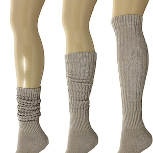 May include: Three pairs of taupe-colored, slouchy knee-high socks displayed on mannequins. The socks have a ribbed texture and vary in the amount of slouching, offering different styling options. The neutral color makes them versatile for various outfits.