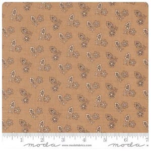 May include: Tan fabric with a repeating pattern of small floral and leaf clusters in shades of brown and cream. The fabric has a textured appearance and a ruler along the bottom edge. The Moda Fabrics logo and website address are printed at the bottom.