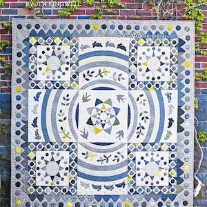 May include: A handmade quilt with a complex design featuring geometric shapes, stars, and animal motifs in shades of blue, gray, and yellow. The quilt has a square shape and is displayed against a brick wall with the text "Burrows + Boughs" by Jen Kingwell.
