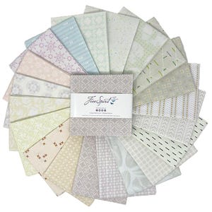 May include: A collection of fabric squares in various pastel colors, arranged in a circular pattern. The fabrics feature diverse patterns, including geometric shapes and floral designs. A central bundle is wrapped with a label that reads "FreeSpirit".