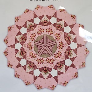 May include: A pink and brown quilt block pattern with a floral design. The text "Playing with Paper Starter Pack" and "Pack 42" is visible.