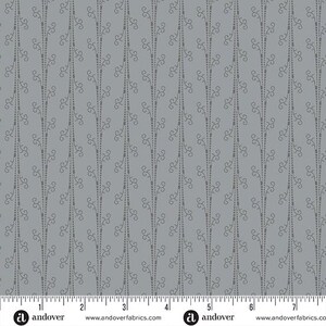 Puede incluir: Una tela gris con un patrón repetitivo de pequeñas flores estilizadas. La tela se mide en pulgadas con una regla en la parte inferior de la imagen. La regla muestra el texto "andover" y la dirección del sitio web "www.andoverfabrics.com".