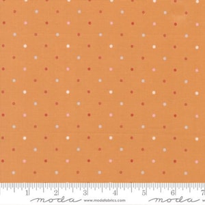 May include: Orange fabric with a repeating pattern of small, evenly spaced polka dots in red, white, and pink. The fabric has a textured appearance and a ruler is visible at the bottom.