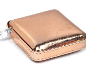Shimmery Rose Gold 60" Retractable Tape Measure, approximately 1.5 inches square, Squeeze the case to release and retract the tape measure