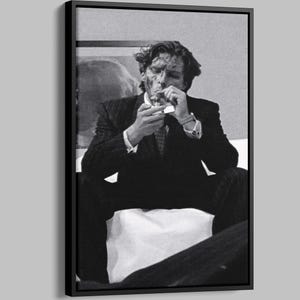 Könnte beinhalten: Schwarz-Weiß-Druck in einem Rahmen einer Person im Anzug, die sich eine Zigarette anzündet. Die Person sitzt, mit einer Uhr am Handgelenk. Das Bild hat eine klassische Film-Noir-Ästhetik.