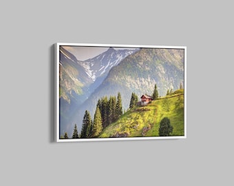 May include: A red cabin nestled in a green mountain valley with a view of snow-capped peaks in the distance.