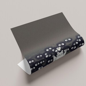 May include: A rolled-up print featuring a whimsical illustration of soot sprites and a friendly forest spirit. The artwork showcases a dark, textured background with white-eyed soot sprites and a light-colored spirit.