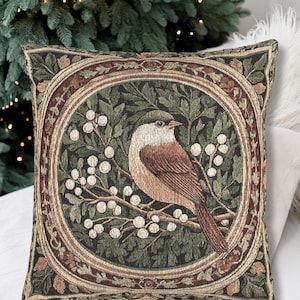 May include: Square decorative pillow with a detailed tapestry design. The pillow features a central image of a bird perched on a branch with white berries, surrounded by a circular frame. The color palette includes shades of brown, green, and cream.