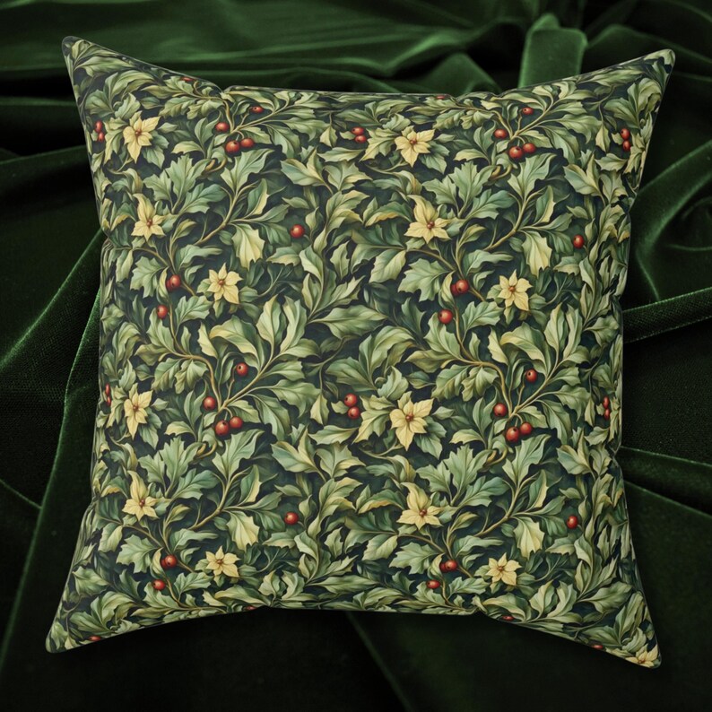 May include: Square decorative pillow with a dark background and a repeating pattern of green leaves, yellow flowers, and red berries. The pillow has a soft, textured appearance and is likely made of fabric.