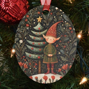 May include: Oval Christmas ornament featuring a whimsical elf standing next to a decorated Christmas tree. The ornament has a dark background with floral and star details. The elf wears a red hat and green coat. A red ribbon is attached for hanging.