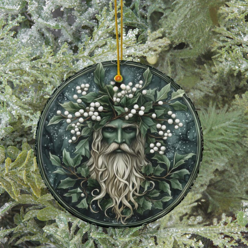 May include: A round ceramic ornament featuring a green-skinned man with a long white beard and hair, wearing a crown of holly and white berries. The background is a dark green with white snowflakes.