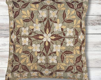 May include: Square decorative pillow with a floral pattern. The pillow features a repeating design of white flowers, brown leaves, and yellow leaves on a green background. The pillow is made of a woven fabric.