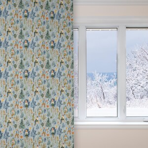 Puede incluir: Una cortina de patr&oacute;n azul y verde con un dise&ntilde;o repetitivo de personas sentadas en un bosque. La cortina est&aacute; colgada frente a una ventana con vista a un paisaje nevado.