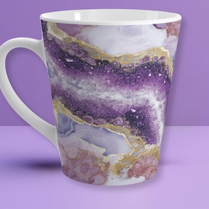 May include: White ceramic coffee mug with a handle, featuring a vibrant design of purple, gold, and pink abstract patterns. The design resembles a geode or agate stone, with crystalline and marbled textures.