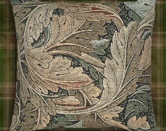 May include: Square throw pillow with a detailed botanical pattern. The design features large, stylized leaves in shades of tan, brown, and green, creating a textured appearance. The pillow is set against a green and brown plaid background.
