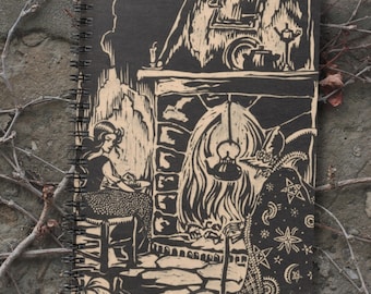 May include: A spiral-bound notebook with a black cover featuring a woodcut-style illustration. The artwork depicts a woman seated near a fireplace, with a witch-like figure in a cloak. The design is in shades of black and beige, with a rustic, vintage aesthetic.