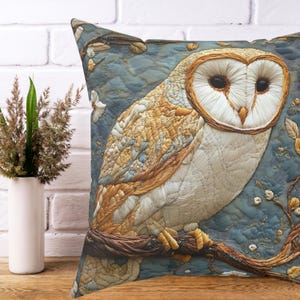 May include: Decorative square pillow featuring an embroidered owl perched on a branch. The owl has white and tan feathers, with a heart-shaped face and dark eyes. The background is a textured blue fabric with floral accents.