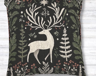 May include: Square decorative pillow with a black background featuring a white deer with large antlers. The pillow has a floral and botanical design in shades of green, red, and white. The pillow is approximately 18 inches square.