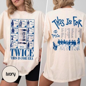 May include: Ivory-colored t-shirt with blue text and graphics. The front features a grid of images and the words "TWICE THIS IS FOR ERA." The back displays "THIS IS FOR TWICE" and a group illustration.