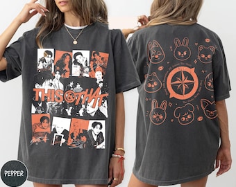 Puede incluir: Una camiseta gris carbón con un collage gráfico frontal de retratos en blanco y negro con detalles en naranja y el texto THIS & THAT. La parte posterior muestra un diseño de brújula naranja rodeado por ocho ilustraciones de animales.