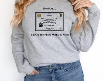 Ouija Board Sweatshirt, Hold On, Im On The Phone With My Mom Ouija Board Crewneck Sweatshirt | Funny Spiritual Graphic  Unisex Heavy Blend