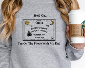 Ouija Board Sweatshirt, Hold On, Im On The Phone With My Dad Ouija Board Crewneck Sweatshirt | Funny Spiritual Graphic  Unisex Heavy Blend