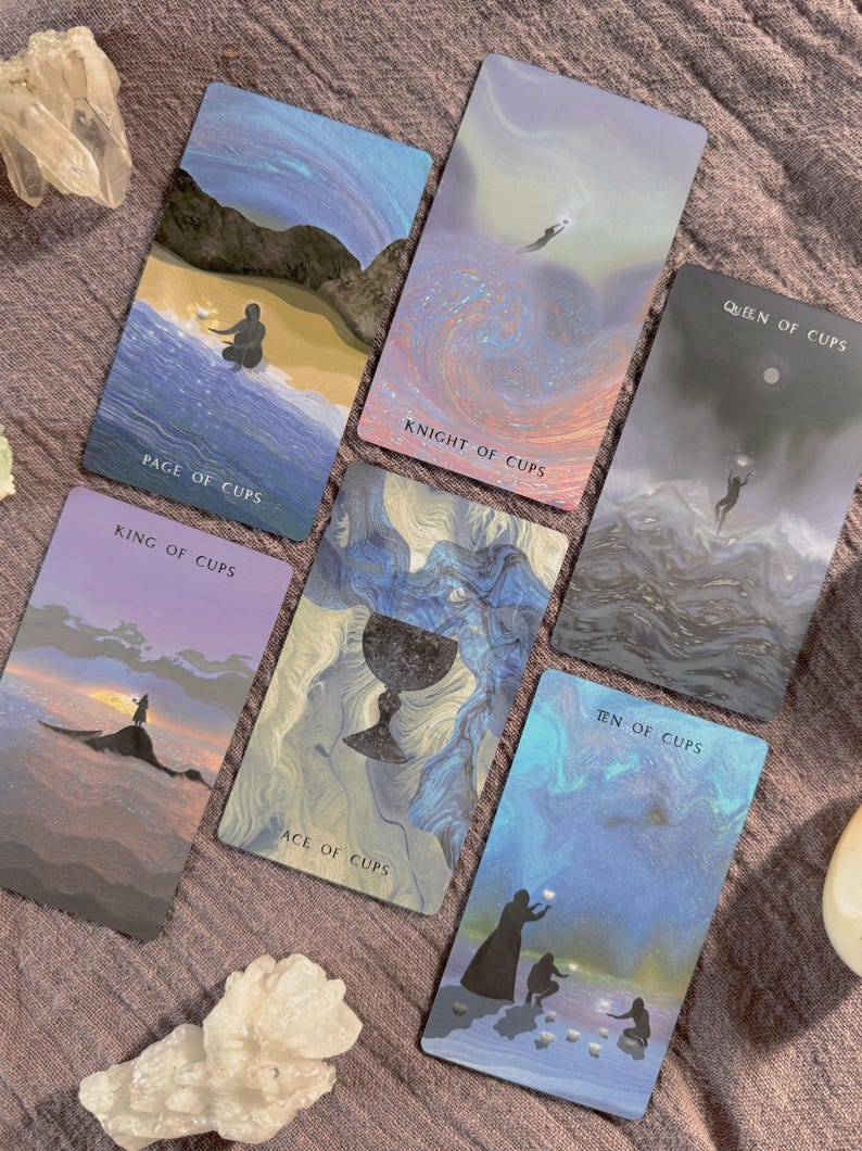 Może przedstawiać: Sześć kart tarota z akwarelowymi ilustracjami i tytułami takimi jak "Page of Cups", "Knight of Cups" i "Queen of Cups". Karty przedstawiają obrazy postaci, krajobraz&oacute;w i kielicha, z miękką, eteryczną paletą kolor&oacute;w.