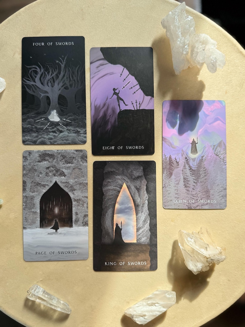 Może przedstawiać: Zestaw kart tarota z tytułami takimi jak "Four of Swords" i "Eight of Swords". Karty przedstawiają mroczne, mistyczne ilustracje postaci i krajobraz&oacute;w. Przezroczyste kryształy g&oacute;rskie są ułożone wok&oacute;ł kart.