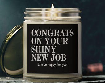 Könnte beinhalten: Eine brennende Kerze in einem durchsichtigen Glas mit einem silbernen Deckel. Das Glas hat ein schwarzes Etikett mit weißem Text, auf dem steht: "CONGRATS ON YOUR SHINY NEW JOB I'm so happy for you!". Ein Glückwunschgeschenk.