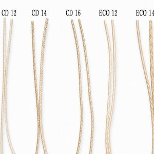 May include: A collection of five types of candle wicks labeled CD 12, CD 14, CD 16, ECO 12, and ECO 14. Each wick is made of braided beige cotton and attached to a circular metal base. The wicks are arranged vertically in a row against a plain background.