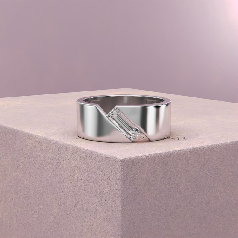 K&ouml;nnte beinhalten: Ein silberner Ring mit geometrischem Design. Der Ring hat einen rechteckigen, klaren Edelstein, der diagonal &uuml;ber einen Teil des Bandes gesetzt ist. Das Band hat einen modernen, minimalistischen Stil mit poliertem Finish.