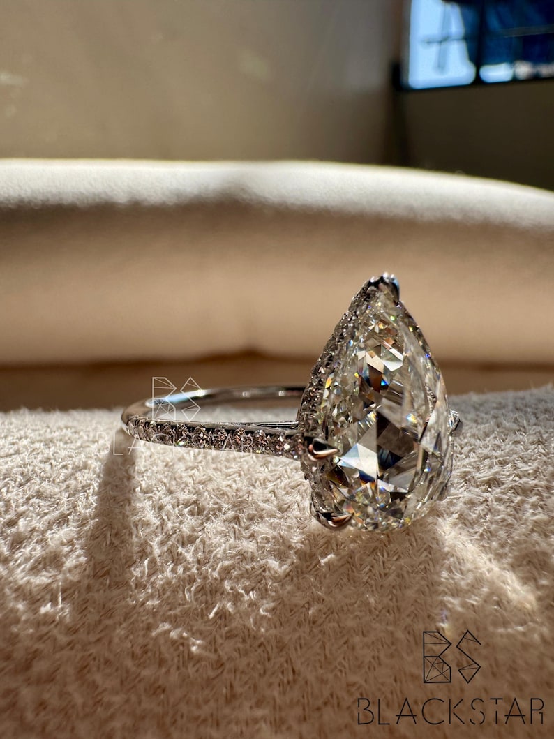Side profile close-up of a pear shaped lab grown diamond engagement ring featuring a sparkling halo and pavé accented white gold band. The elongated pear diamond is expertly set to maximize light performance and elegance. Designed for modern brides, this ring combines luxury with sustainability, making it ideal for searches such as pear lab diamond engagement ring, ethical diamond jewelry, luxury bridal ring, and contemporary fine jewelry designs.