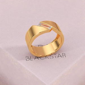 K&ouml;nnte beinhalten: Ein goldfarbener Ring mit geometrischem Design. Der Ring hat einen rechteckigen Edelstein und zwei kleinere Steine. Das Wort "BLACKSTAR" ist auf der Oberfl&auml;che darunter aufgedruckt.