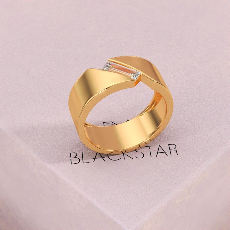 K&ouml;nnte beinhalten: Ein goldfarbener Ring mit geometrischem Design. Der Ring hat einen rechteckigen Edelstein und zwei kleinere Steine. Das Wort "BLACKSTAR" ist auf der Oberfl&auml;che darunter aufgedruckt.