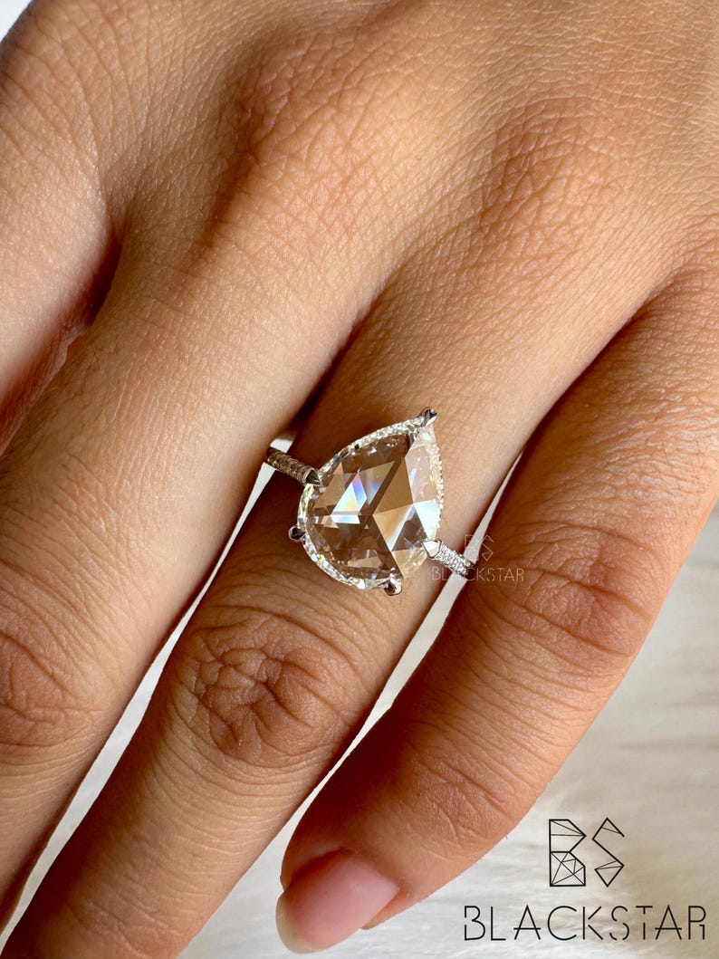 Side profile close-up of a pear cut lab grown diamond engagement ring showcasing the elevated setting, halo diamonds, and pavé accented white gold band. The refined prong work enhances light performance while maintaining a sleek, modern profile. Perfect for buyers searching pear shaped diamond engagement rings, lab grown diamonds, ethical bridal jewelry, luxury handmade rings, and contemporary engagement ring styles.
