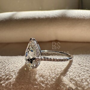 Side angle view of a pear cut lab grown diamond ring emphasizing the pavé diamond band and refined prong work around the halo setting. The white gold band offers a sleek, elegant finish while enhancing durability and comfort. This sophisticated engagement ring suits customers looking for pear shaped diamond rings, lab grown diamonds, ethical engagement rings, sustainable fine jewelry, and premium handcrafted bridal jewelry.