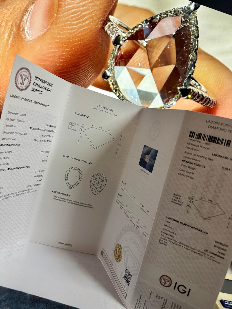 Close-up image of an IGI certified pear shaped lab grown diamond engagement ring displayed alongside its official International Gemological Institute laboratory grown diamond report. The pear cut diamond features exceptional brilliance, halo detailing, and pavé white gold band craftsmanship. This certified lab grown diamond ring highlights authenticity, ethical sourcing, and premium quality, ideal for buyers searching IGI certified lab diamond rings, pear shape engagement rings, fine jewelry