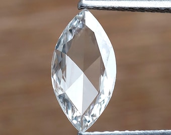 Könnte beinhalten: Ein klarer, facettierter Diamant in Marquise-Form, der von einer Pinzette gehalten wird.
