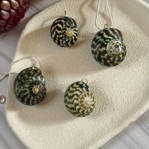 May include: A white ceramic mug with a black handle and the text "But First, Coffee" in a black, handwritten-style font. The mug is on a white surface.