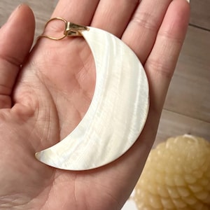 Può includere: Collana con pendente a forma di mezzaluna. Il pendente è di colore bianco perlaceo con una cauzione color oro e una delicata catena d'oro. La forma della luna ha una superficie strutturata.